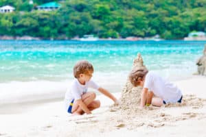 two twin boys building a sand castle on the beach