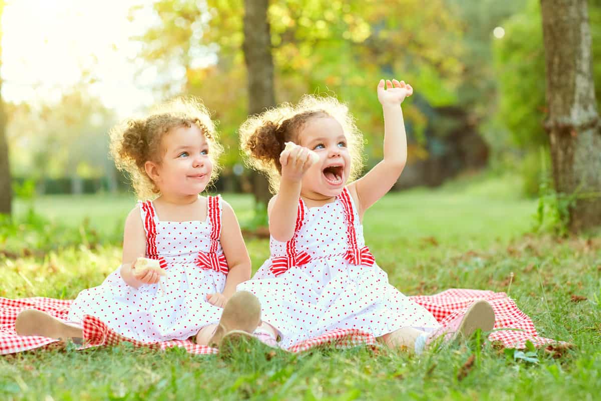 Twin girls in matching white dresses with pink bows